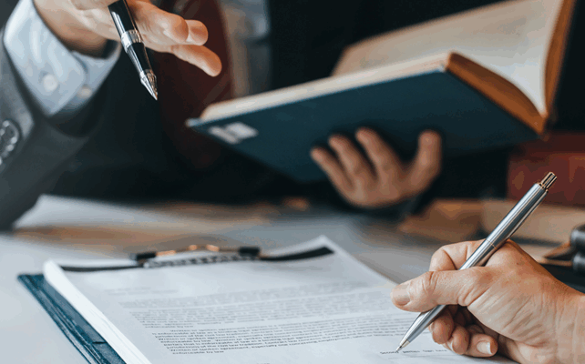 Professionista ad un tavolo con libri e blocchetto di documenti
