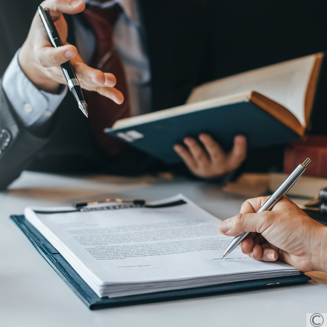 Professionista ad un tavolo con libri e blocchetto di documenti